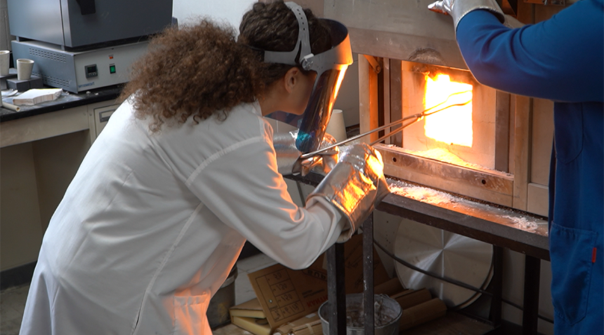 student working with materials in a fire oven